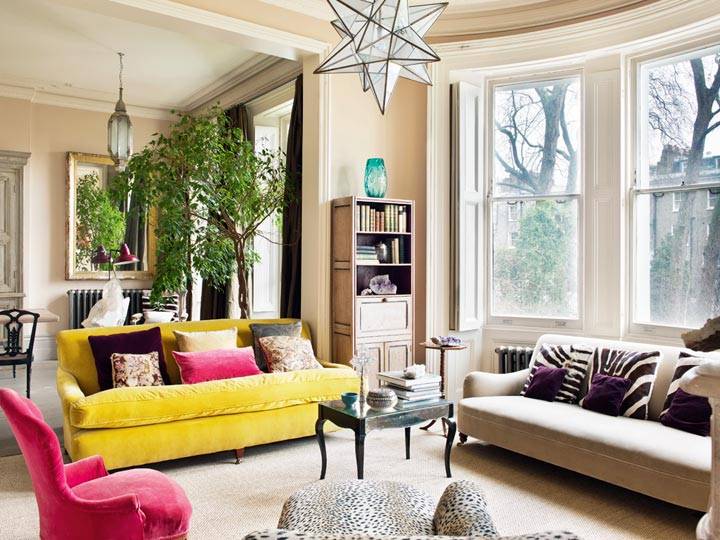 желтый диван и розовое кресло в комнате с эркером