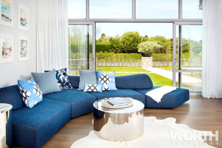 Уютный синий диван в комнате с выходом на террасу