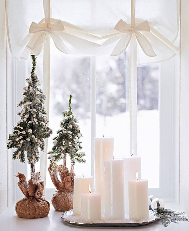 белые свечи и маленькие ёлочки на окне дома
