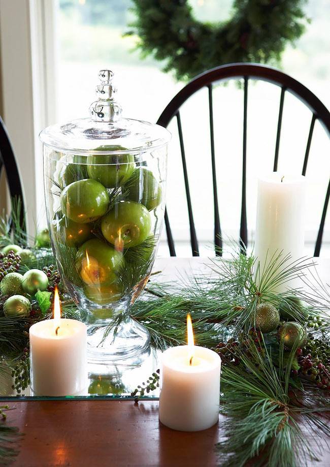 стеклянная ваза с зелеными яблоками и свечи на столе