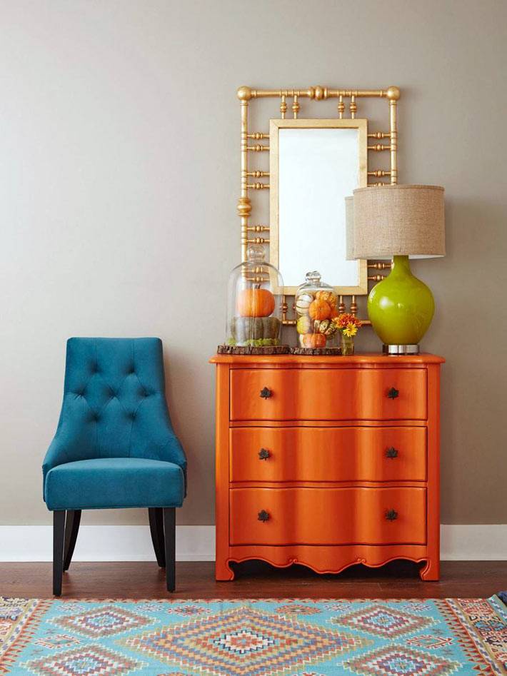 яркий оранжевый комод и синий стул в интерьере