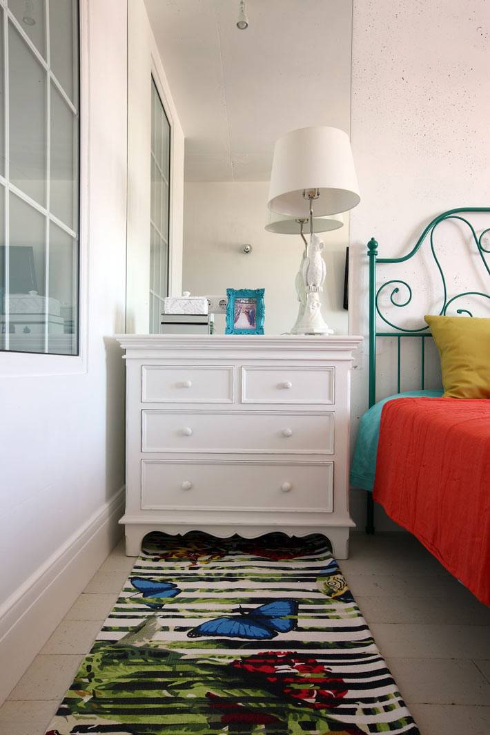 Белый комод и красивый придиванный коврик в спальне