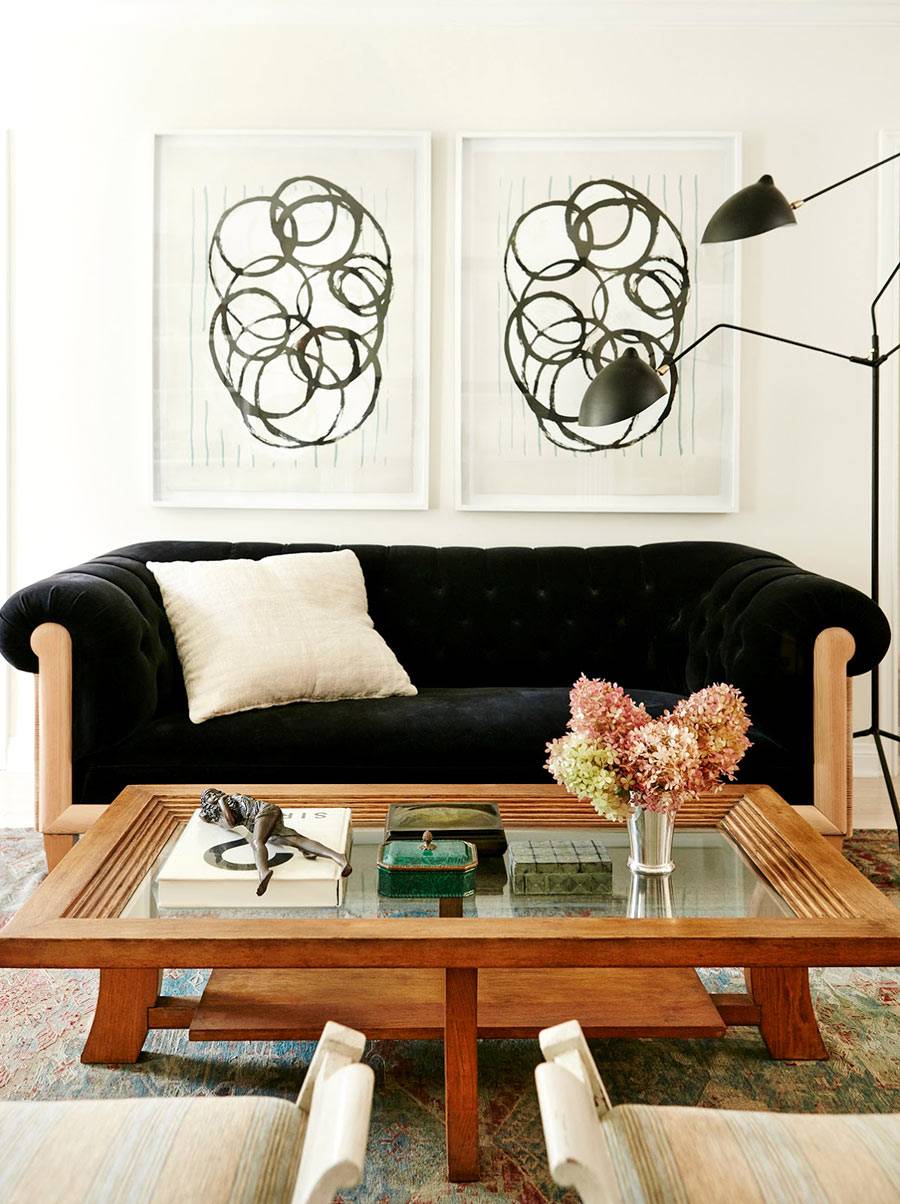 черный диван и абстрактные картины украшают интерьер гостиной комнаты