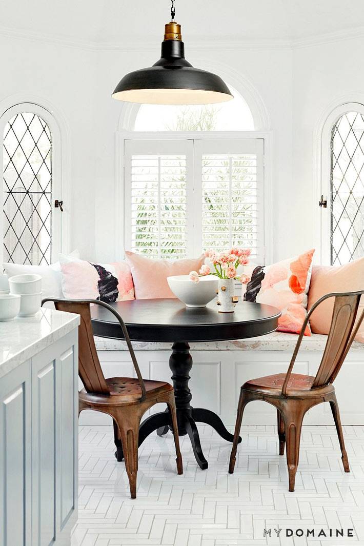 Светлое пространство с нежными розовыми подушками возле круглого стола