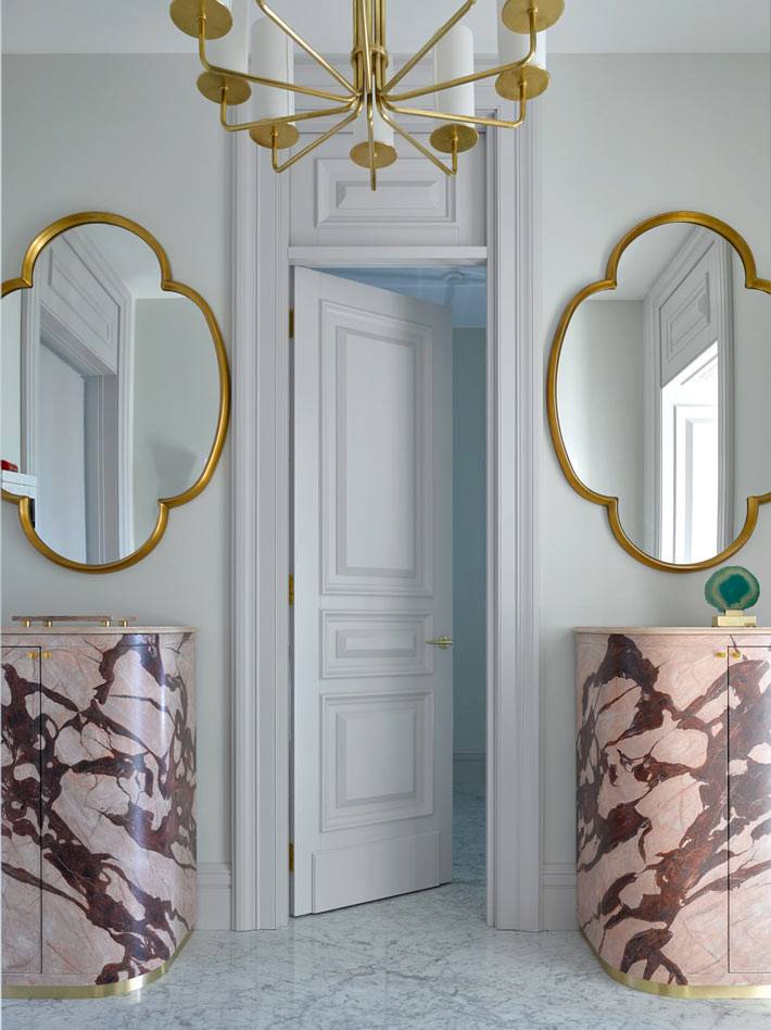 симметричные зеркала в прихожей комнате и мраморные тумбы