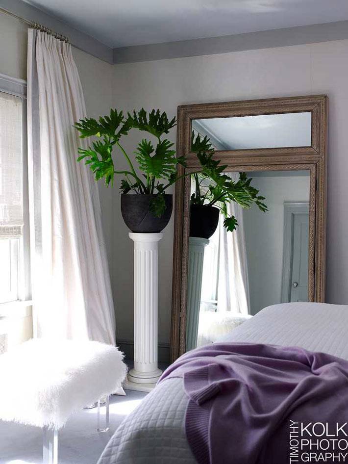 белый текстиль в спальне с большим зеленым комнатным растением