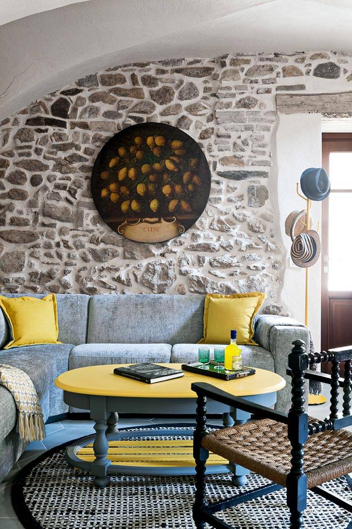 сочетание серого и желтого цвета в гостиной с каменными стенами фото