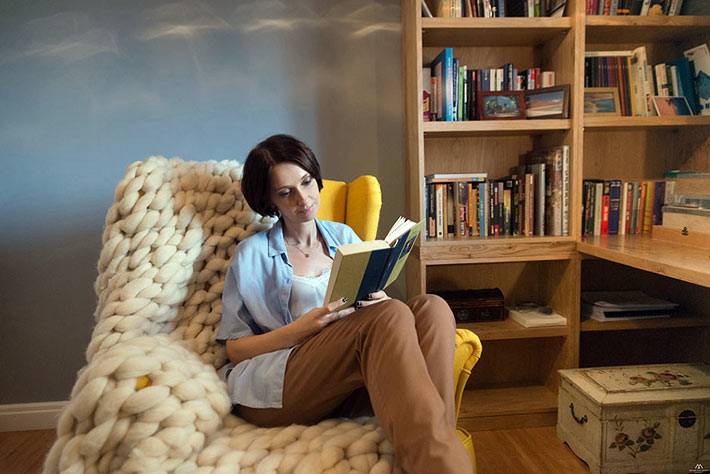 комфортное кресло и плед для чтения в комнате с книгами