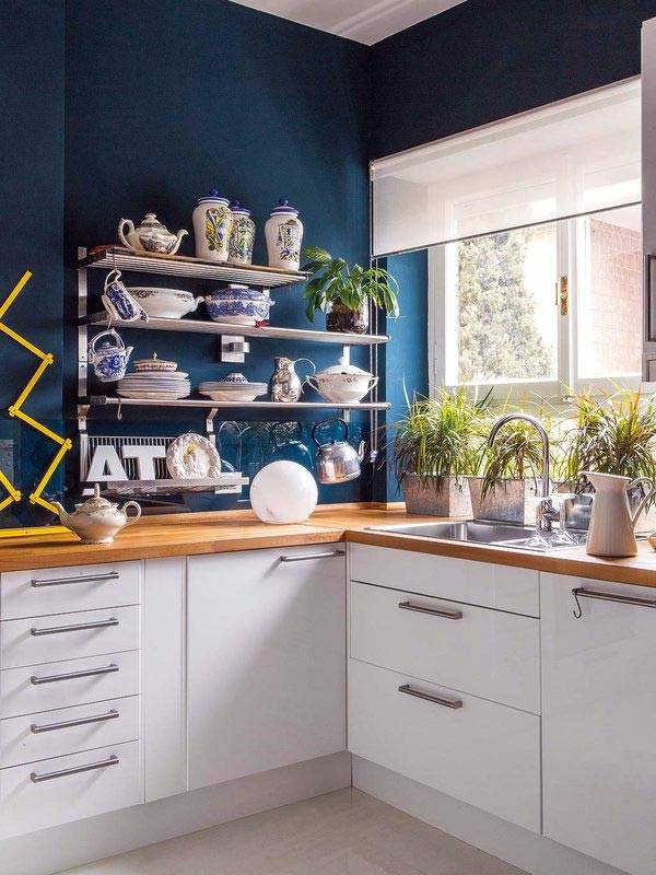 синие стены на кухне, открытые полки для посуды и окно перед раковиной
