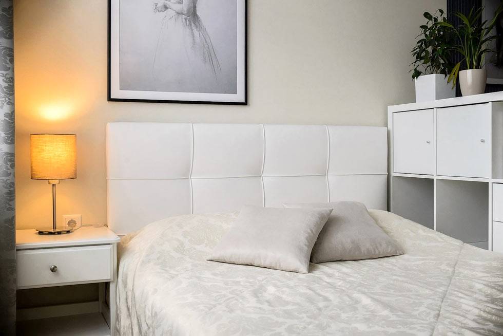 белая кровать с мягким изголовьем и картина с балериной