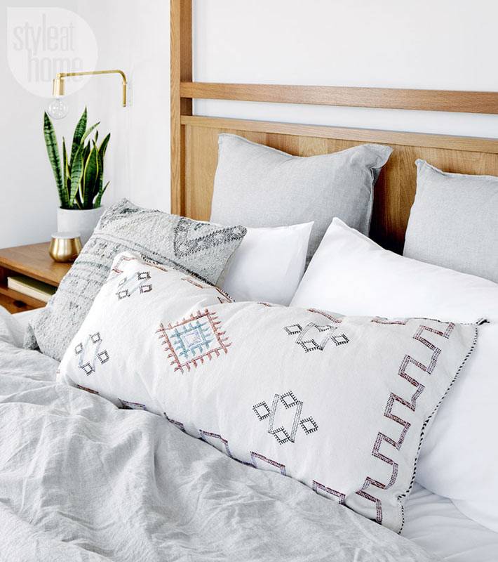 деревянная кровать в спальне и серое постельное белье фото