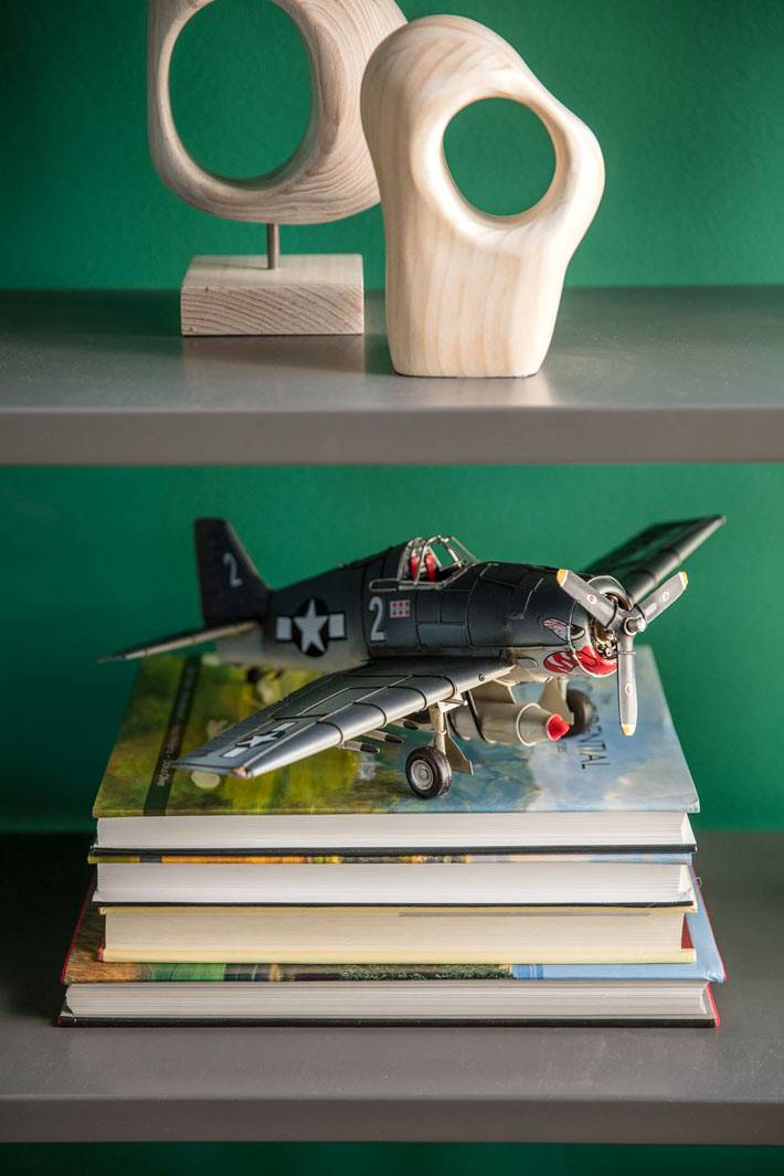 фигурки-декор из дерева и модель самолета на полках стеллажа
