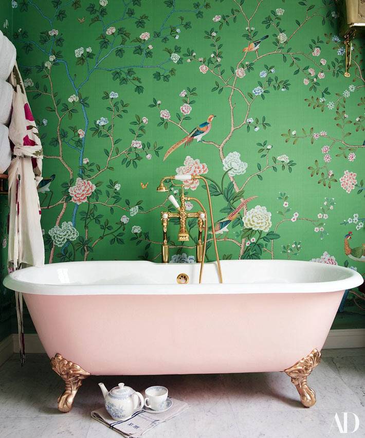 розовая ванна на ножках на фоне зеленой стены с обоями